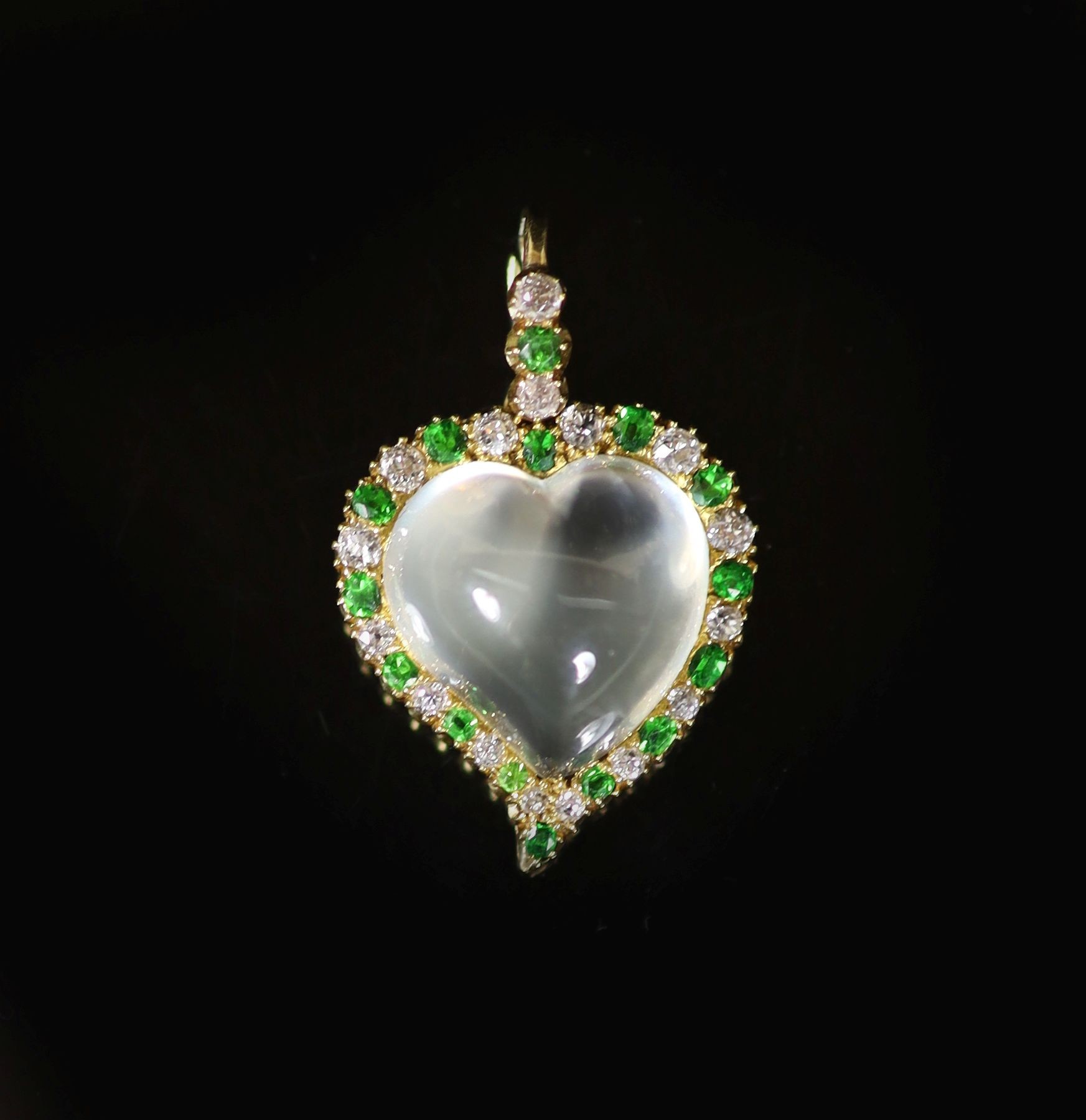 An early 20th century gold, moonstone, diamond and green garnet set heart shaped pendant